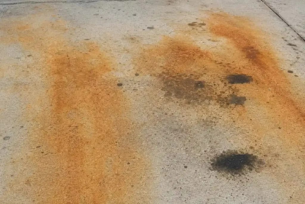 Driveway Replacement vs. Restoration: The $8,000 Question 4 Orange Rust Staining and Oil Stains ona concrete driveway Surface in Miami, FL