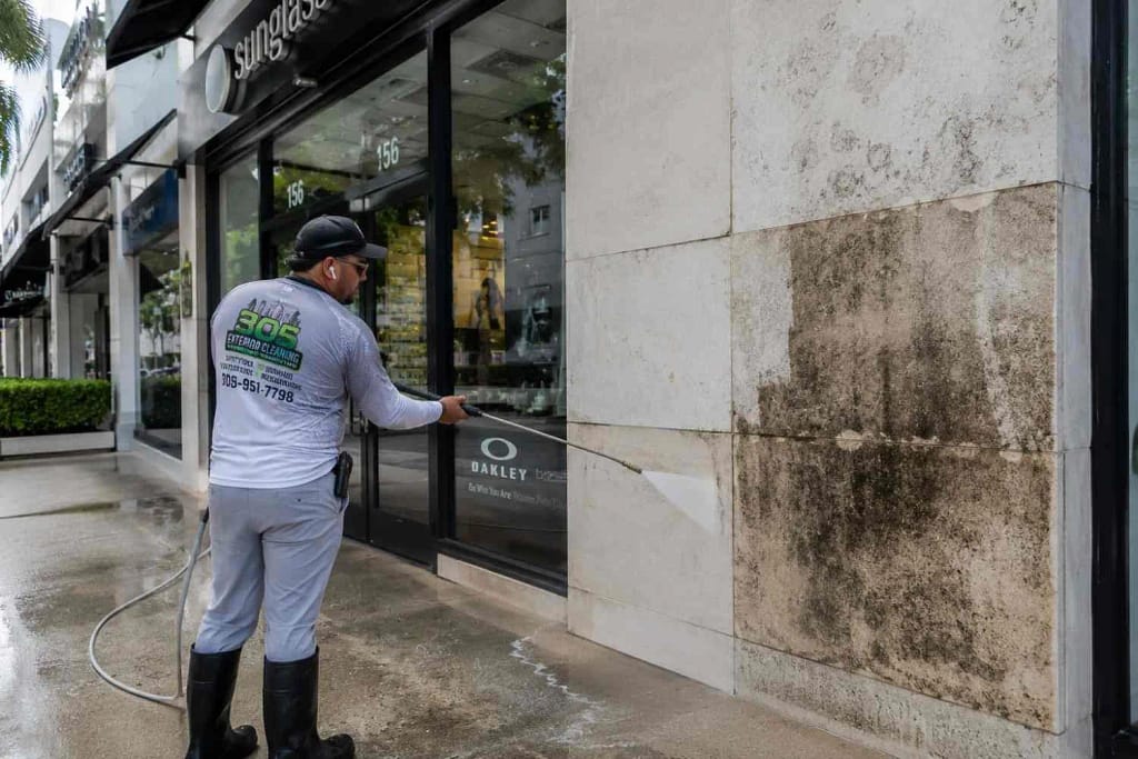 Commercial vs Residential Pressure Washing in Miami: What's the Difference? 4 Professional cleaning a commercial storefront sidewalk in Miami FL business district
